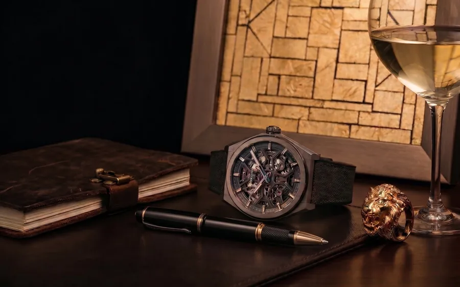 A skeleton watch, a pen and a ring beside a framed gold work, Art & Luxury day